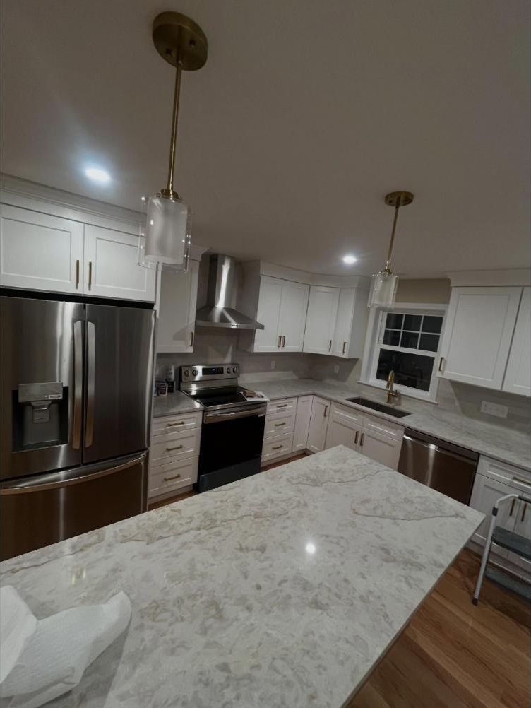 Finished kitchen with white cabinets, stone island and stainless appliances