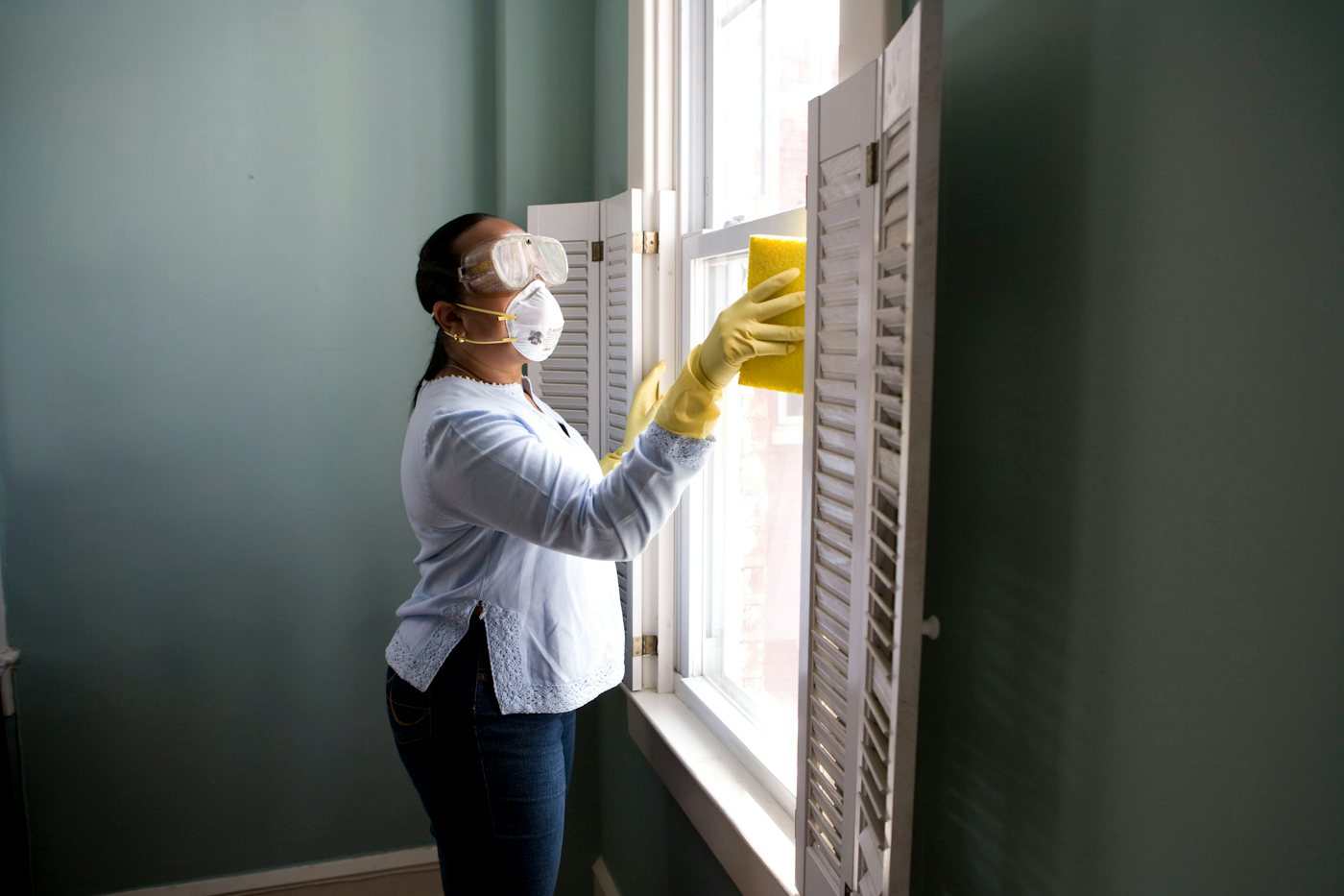 Cleaner in yellow gloves wiping a window